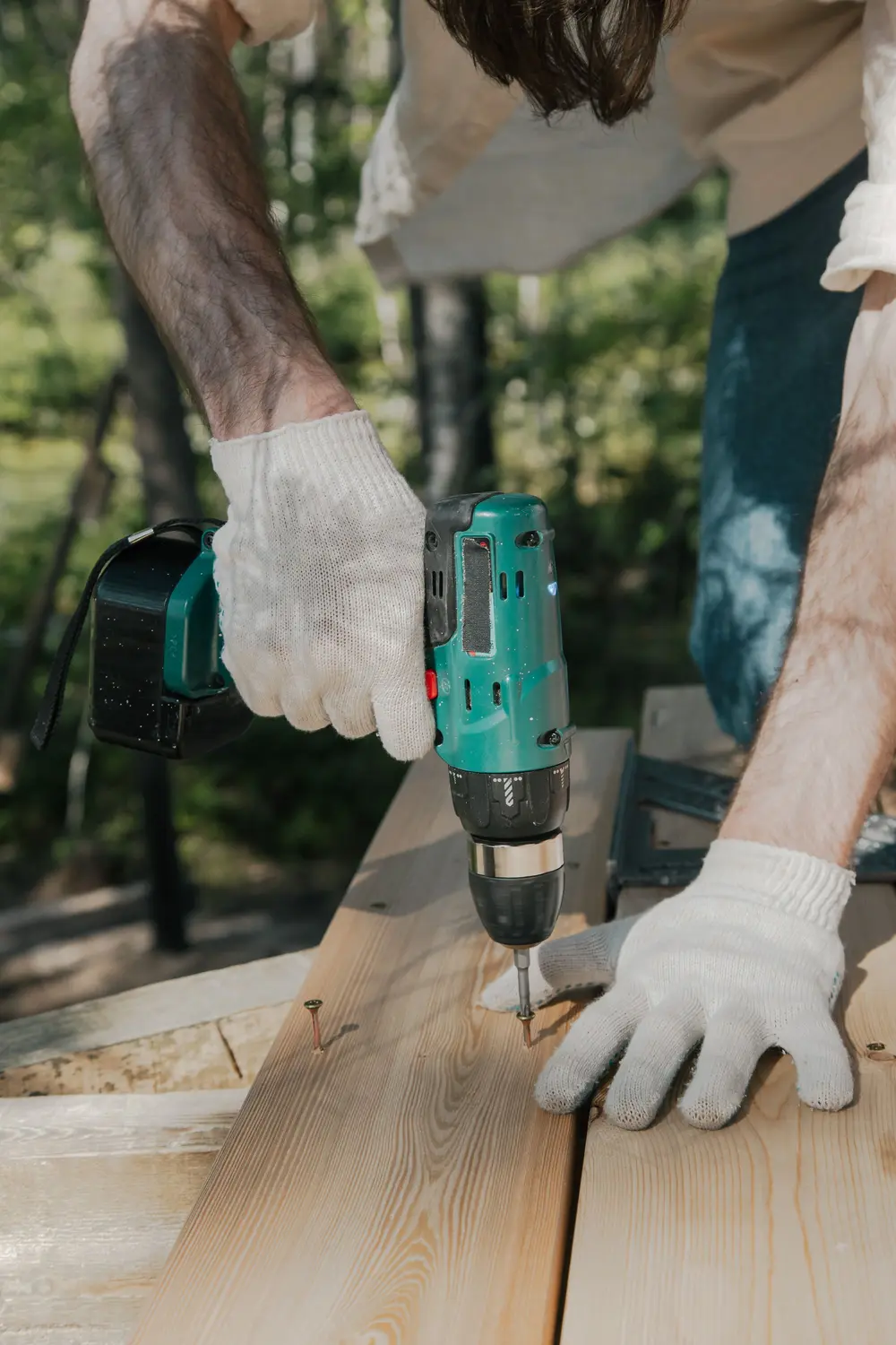 Gloved hands driving screws into new deck boards
