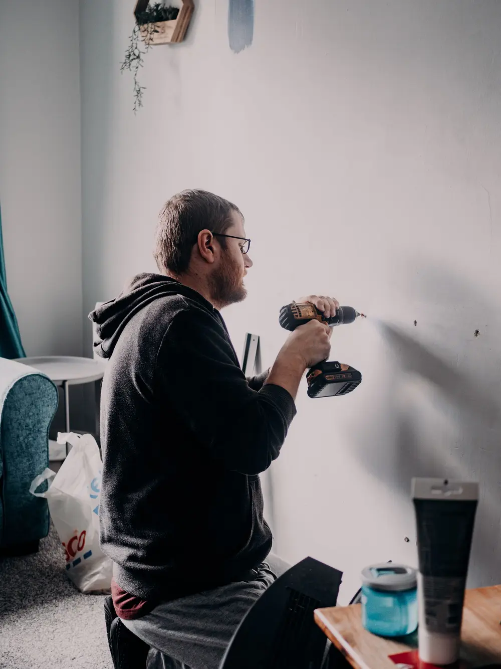 Handyman drilling into a living room wall to mount a fixture