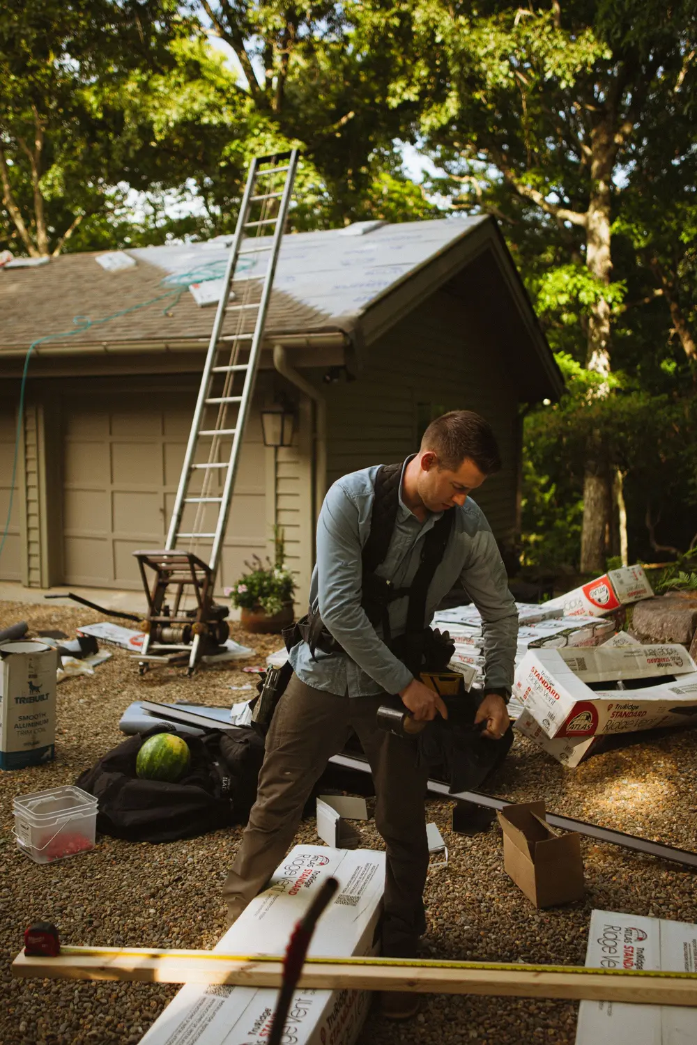 Contractor cutting material outside a house with a ladder set against the roof