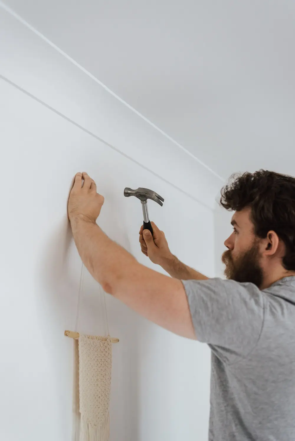 Handyman driving a nail into a freshly painted wall during a home repair