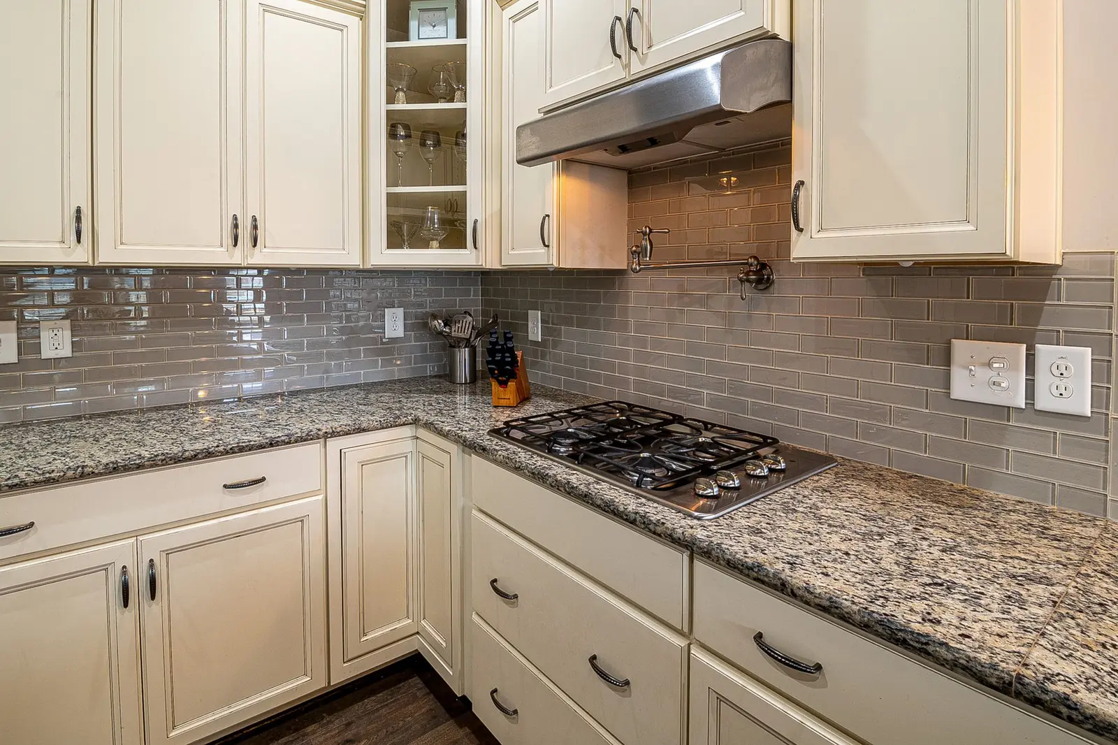 Kitchen with a stainless vent hood, granite counters and white cabinets