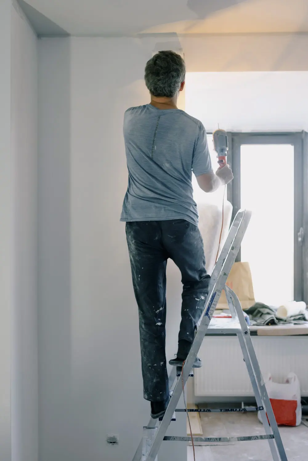Contractor on a stepladder working on a ceiling in a bright room
