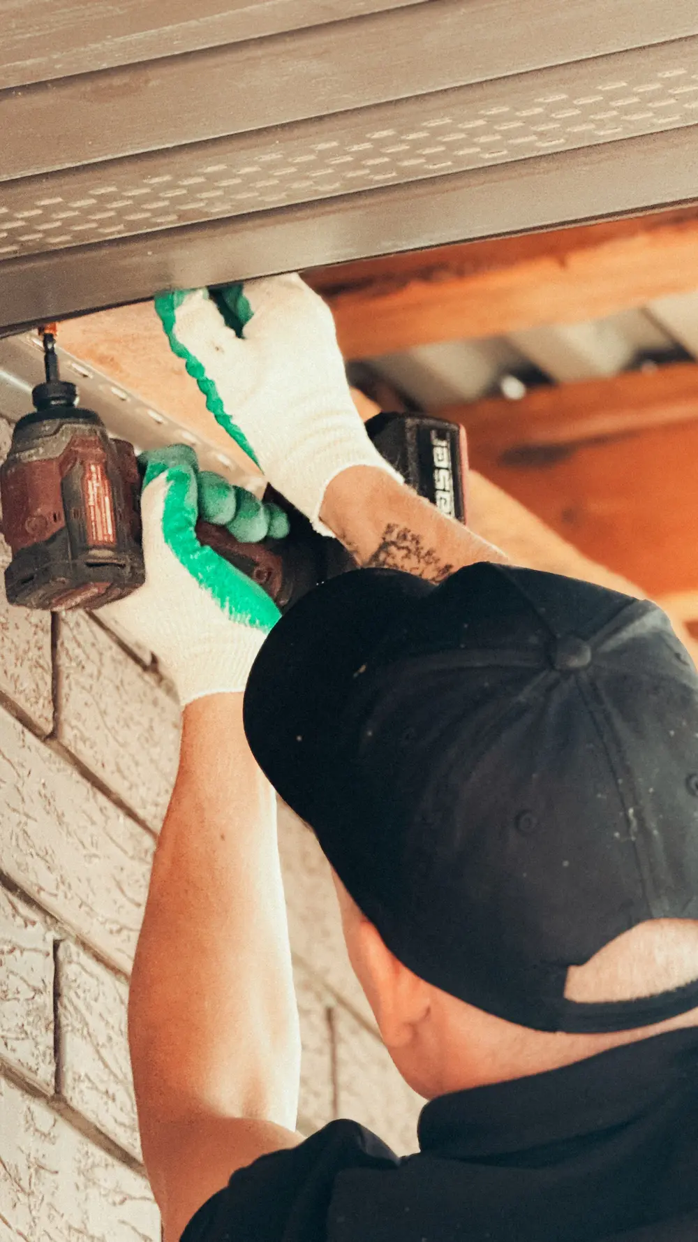 Installer mounting an outdoor light fixture under a porch ceiling