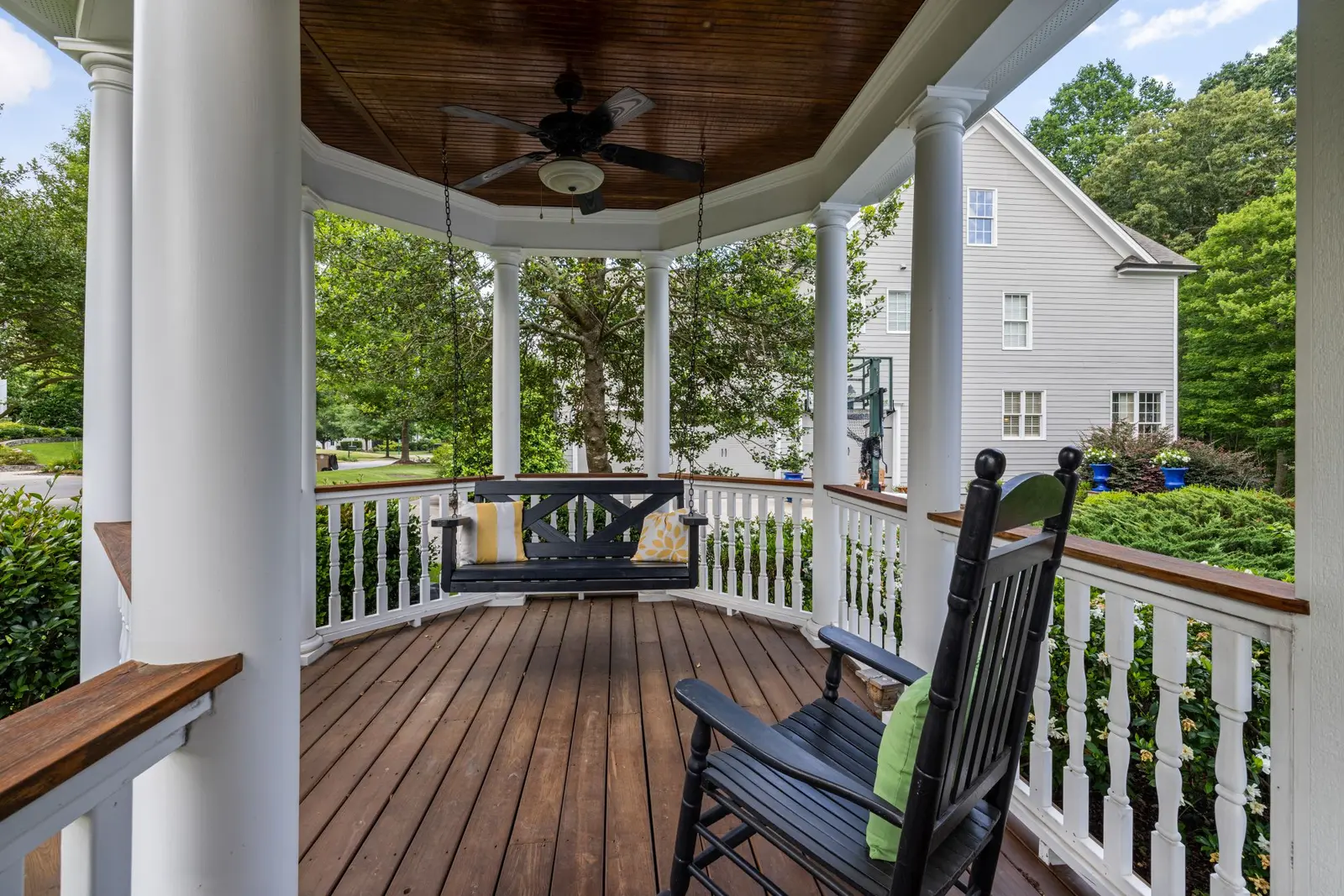 Covered porch with wood deck boards and white railings
