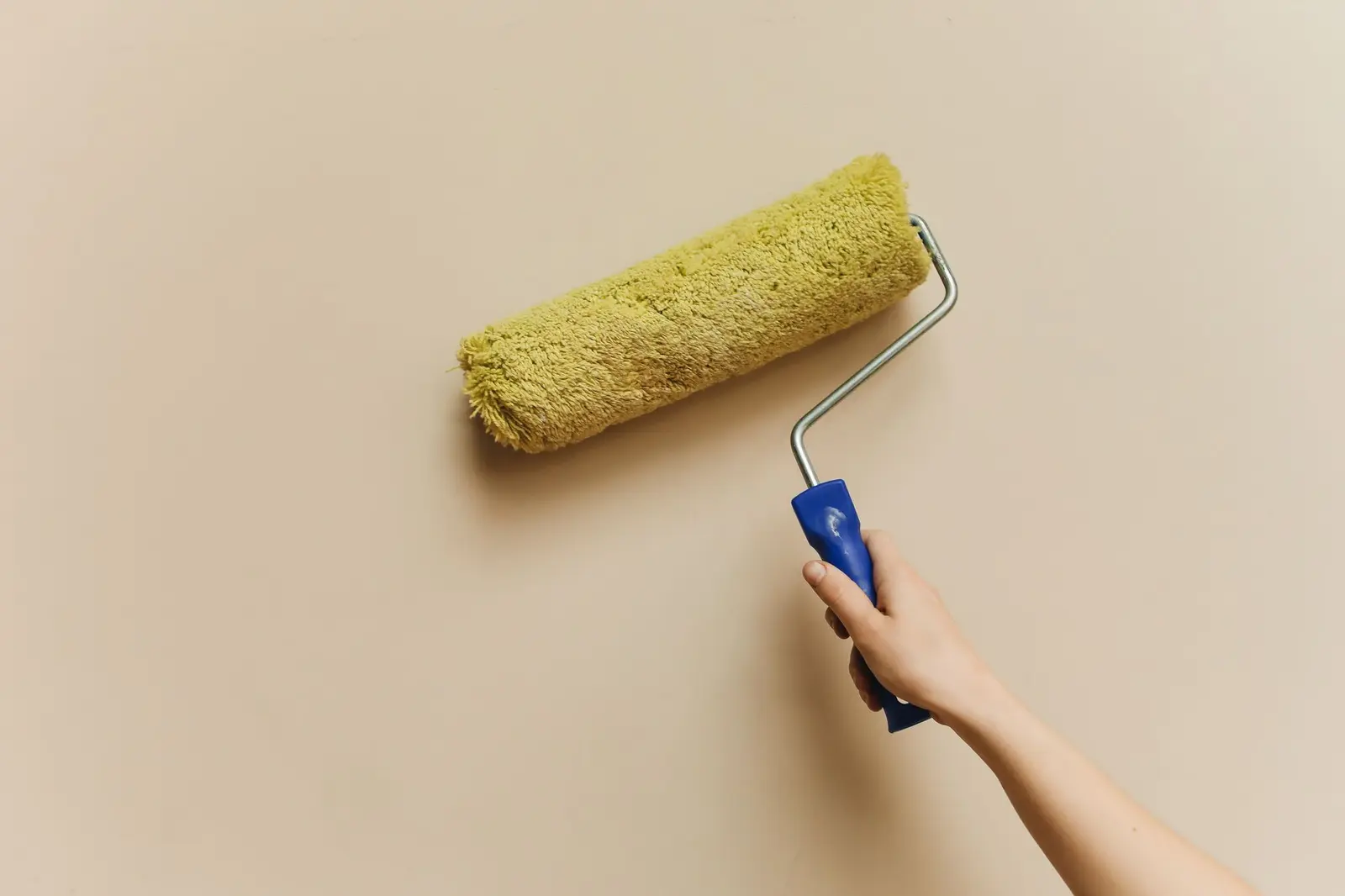 Paint roller laying a warm cream coat on an interior wall