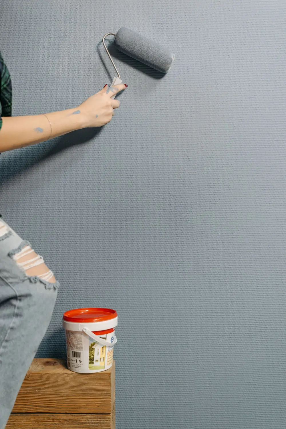 Painter rolling a grey coat on an interior wall