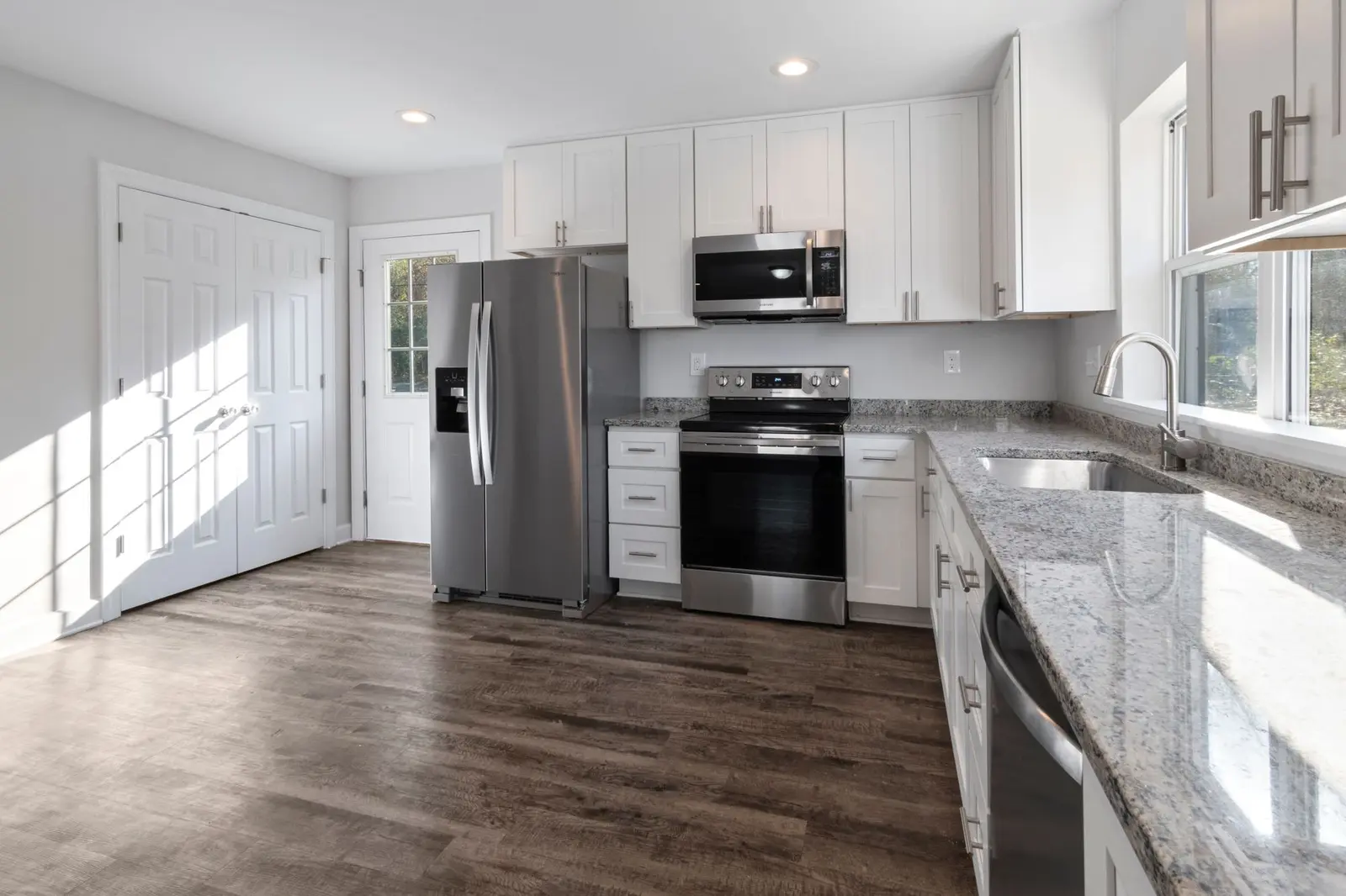 Finished white kitchen with stainless appliances and wood-look floors